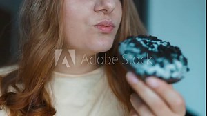 Close up portrait of a hungry 30s woman eating donuts with white frosting.Girl sniffs sweet pastries. Eating donut when takeout and delivery. Fast food takeaway back home. High quality FullHD footage