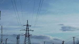 Overhead Power Line, Transmission Tower, High Voltage Line, Voltage and Beautiful Time Lapse of the Blue Sky and Clouds on a Clear Day. Transmission Line, Overhead Power Line, Power Grid.