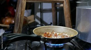 Frying bacon in a frying pan. Close-up shot: fried bacon inside a skillet. Pieces of fried bacon in a cooking pan. Preparing dinner. Cooking. Homemade food. Steaming frying pan isolated on the stove.
