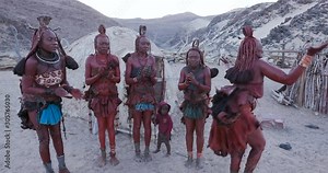 4K view of Himba woman in traditional dress dancing and singing outside their clay hut, Namibia