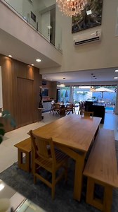 This elegant, open-plan dining room combines warmth and luxury with a touch of modern design. Integrated with a minimalist style kitchen equipped with the latest equipment, this space offers comfort and function in one unit. A long dining table made from premium materials, such as solid wood or marble, surrounded by ergonomically designed chairs, creates a luxurious but still comfortable atmosphere. A large glass wall faces directly onto the swimming pool, providing a calming view while bringing