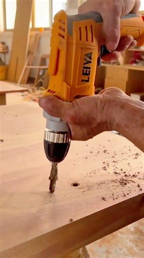 wood drilling process using electric hand drill to create precise circular holes in timber board
