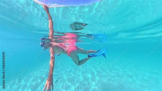 Woman enjoying tropical vacation while snorkeling underwater, wearing pink bikini, mask, and fins in the beautiful, clear turquoise waters of Anse Figuier beach, Martinique, Caribbean of France