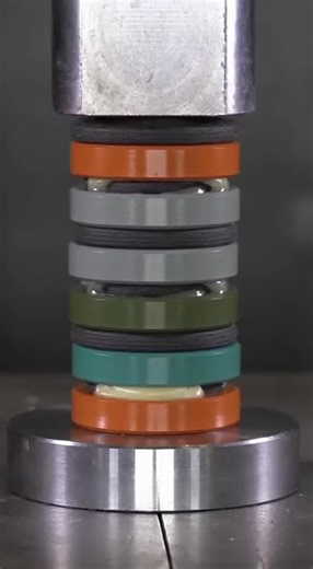 Nic Davis on Instagram: "Watch as a towering column of industrial alloy discs in vibrant Cerakote colors gets slowly crushed by a hydraulic press. As the pressure builds, the spacers compress and colorful lubricant oozes out in the most satisfying way possible."