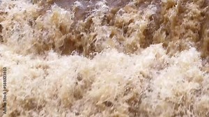 Muddy flash flood waters churn in a river current after a torrential storm, 30fps