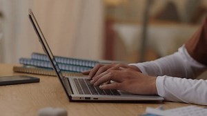 Cropped shot of hands of unrecognizable student typing on keyboard of wireless pc when working on educational project at desk