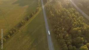 On a bright summer day, a drone flies over the highway along which cars and trucks with trailers move in the stream, transporting their goods across the country. Delivery of goods to any distance