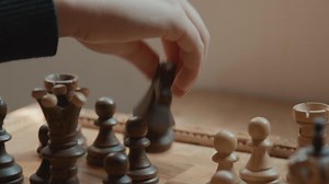 Hand of girl moving and removing chess pieces on chessboard