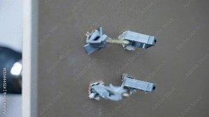 Process of screws fixation in drywall holes with plastic dowels, electric screwdriver assembling screw and fastening with dowel, wok with drywall and screws for fixation