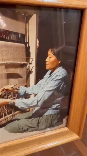 A beautiful moment of tradition and skill: a talented Navajo weaver focused at her traditional loom, carefully working the intricate geometric patterns of a vibrant wool rug. Captured in a cozy workshop setting, this photo celebrates the enduring art of handwoven textiles passed down through generations. #NavajoWeaving #IndigenousArt #HandmadeWithLove | Nizhoni Ranch Gallery