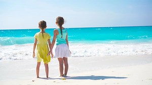Adorable little girls walking on the beach. Back view of kids together enjoy sea view