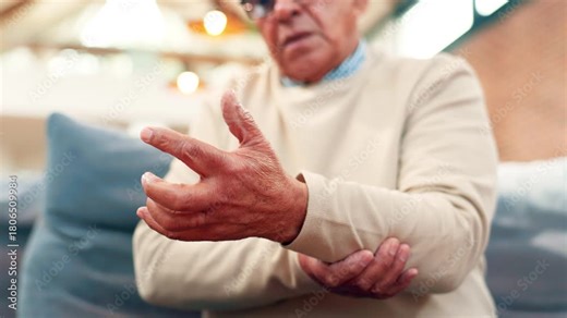 Hand pain, cramps and arm with old man on sofa for osteoporosis, joint injury and inflammation. Arthritis symptoms, fibromyalgia and sprain with person in living room of home for carpal tunnel