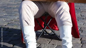 Folk musician in traditional Russian clothes plays an old Russian musical instrument gusli on the background of the Kremlin on red Square. Moscow, Russia