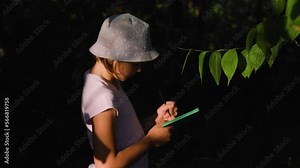 pretty children girl Naturalist Scientist Explores Plant Life and Insect Life take notes in his notebook. Smart Curious kid Botanist and Entomologist Explores Nature.