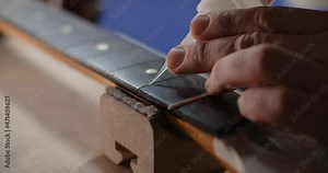 Luthier adds glue to the fretboard before pressing in the new guitar frets. Repairing the guitar, crafting the musical instruments, 4k 60p Prores HQ