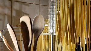 drying homemade noodles. tagliatelle, Italian pasta freshly made and left to dry on the dryer. view with wooden ladles at the side and flour.