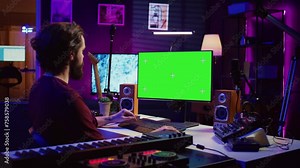 Music producer learning to use mixing console and soundboard, using online tutorial lesson on greenscreen. Artist learns to edit songs and add audio effects, mixing and mastering tracks. Camera B.