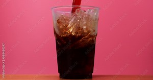 4K footage Front view Close-up SLO MO Pour black coffee into a glass on pink background.