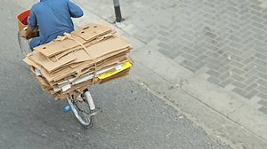 Dubai, UAE - 22nd August 2024: Urban Jungle Sustainability: A 4K Journey into the Life of a Bicycle Recycler. A Pakistani Man riding bicycle With Loaded Cartons.