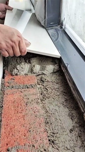 installing large white ceramic tiles on a window sill with thick gray cement mortar for home repair