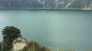 View of Quilotoa Lake, an ancient volcano and starting point for the Quilotoa Loop hike with mist close to the green water