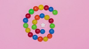 Star candy surrounded by chocolates on a pink background - Free Stock Video