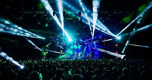 Download View from the auditorium of a crowd of spectators and a stage with musicians at a rock concert in the light of spotlights for free