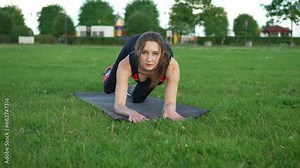 Front view woman does elevation leg with gymnastic elastic bands on mat pumping muscles of thigh and buttocks. Fitness training in fresh air. Female gymnastics. Butt workout motivation