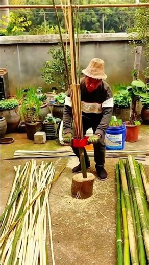 a special red manual tool to split a long green bamboo pole into several thin strips easily