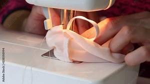 A woman sews a protective mask from fabric. On a sewing machine. Work at home.
