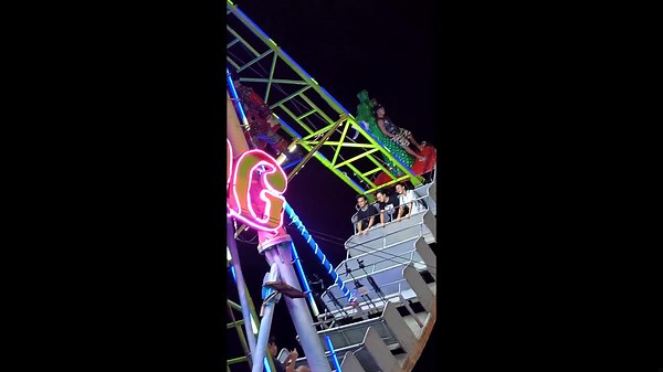 Ride operator casually stands on the back of swinging pirate ship