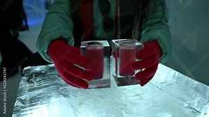 Ice glass with colorful drinks served on an ice-made table. Winter travel to ice hotel.