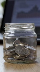 Time lapse money coin in a glass jar grows on the background of financial charts. Concept financial business investment. Close-up, Vertical footage