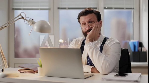 Boredom, fatigue, burnout concept. Sleepy man in office at computer looks tired and exhausted, tired worker yawns and feels bored and stressed