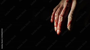 Close-up of a hand dripping blood against a dark background, creating a dramatic and emotional mood in the image