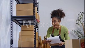 Warehouse employee managing stock and taking notes on a clipboard. Focus on organization and detailed inventory keeping