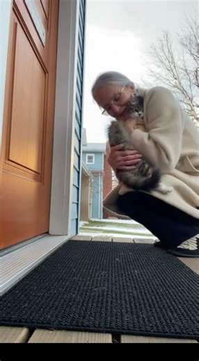 Old Woman Gives A Hug The Cat in Front Of Her Door