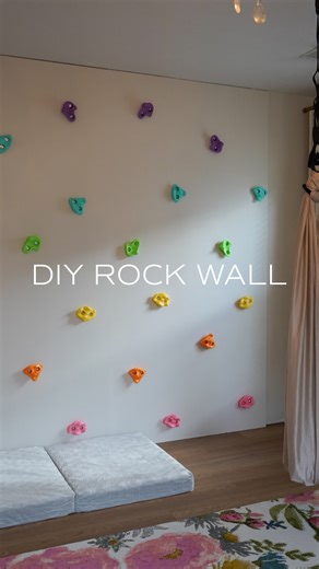 Playroom Makeover: DIY Rock Wall 🪨 If you have an active toddler like I do, this is beyond worth it to build! She hasn’t gotten off it in 2 days lol. Plus it helps build strength and body awareness 🙌🏼 Comment “PLAYROOM” for a full materials list! General Items: -3/4” plywood -4” construction screws (screw into studs!) -drywall mud -primer -paint -drill / drill bits -climbing rocks I’m thinking we should add monkey bars up the side and across the top 🙈 and maybe some ropes / other anchors for