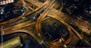 Loops, highways and freeways with numerous moving cars. Top view on Los Angeles interchange in the evening.