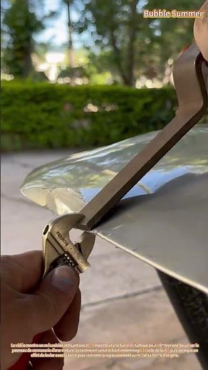 Réparation de carrosserie automobile : élimination d'une bosse à l'aide d'une clé et d'un levier