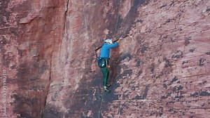 Female rock climber skillfully and technically moves up a steep sandstone wall