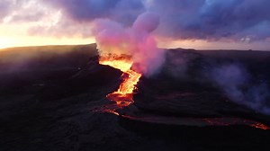 Premium stock video - A swiftly flowing volcanic lava scene captured by a 4k drone, featuring aerial cinematic footage, imbued with drama, set against a backdrop of an orange, cloudy sky