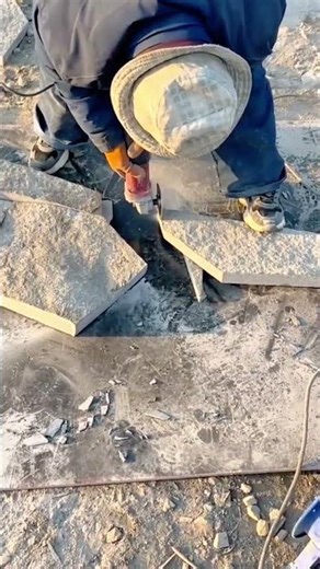 Worker cutting stone slab using angle grinder tool handheld