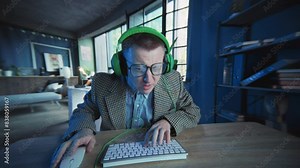 Emotional guy with glasses and headphones use computer typing on keyboard look on screen. Geek. Active work. Office or apartment