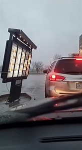 Drive-Thru Menu Board Topples Onto SUV During Wind Gust 🌪️ Amarillo, Texas — March 28, 2024 Dashcam footage from a car waiting in a fast-food drive-thru captures a sudden accident on a very windy afternoon. As strong gusts whip through the lane, the large menu board beside the vehicle ahead begins to wobble before its metal base separates from the concrete. Within seconds, the entire sign structure tips over and crashes onto the roof of the SUV waiting to order, forcing the vehicle’s suspension