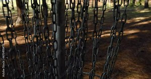 Dolly shot walking towards a frisbee golf basket and throwing a white frisbee golf disc into it. 4k