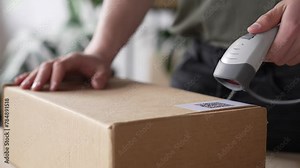 Warehouse worker using a QR code reader, scanning parcels into the system, worker checking goods packages and making inventory of goods
