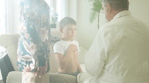 Pediatrician performs a health check on a young boy at home, emphasizing care and compassion. Concept of in-home healthcare, pediatric consultation, and family-focused medical support.