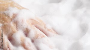 Female hands are washing with soap bubbles. Woman plays with fluffy foam in bathtub, macro. Lady holds handful of soap bubbles, close up.