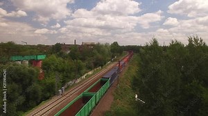 Electric freight train, locomotive moves rides by rail with wagons, transportation, deliver container, transports cargo in city, town. Aerial view, drone, air shoot